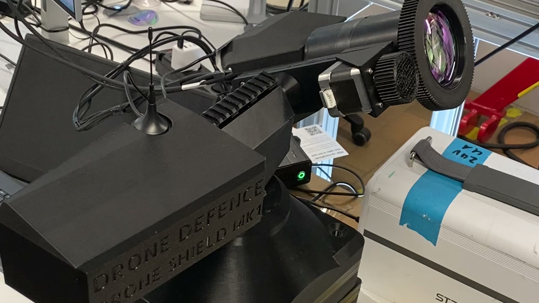 The BeamSentry MK1 turret on the bench: pan-tilt head with beam expander and tracking camera, marked DRONE DEFENCE · DRONE SHIELD MK1.